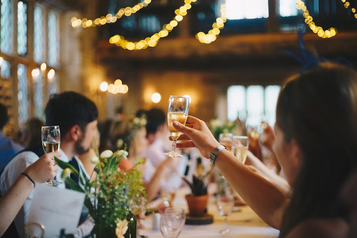 Guests raising a toast together beneath warm string lights.